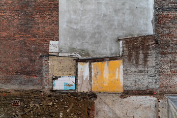 Wall showing the remains of a demolished house after being token down. Brick walls, tiles, painted and plastered surfaces with different structures and textures. Lost place background.