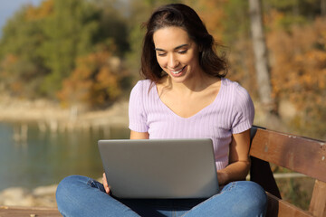 Happy woman in nature using laptop