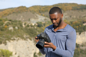 Man with black skin checking photos on dslr camera