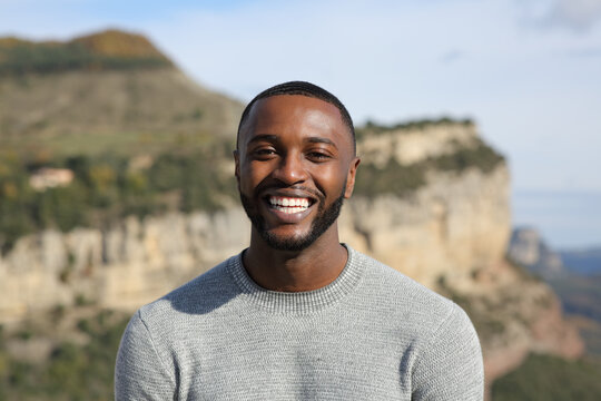 Happy man with black skin smiling at camera in the mountain