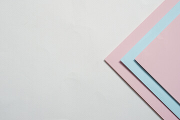 On a white background, an abstract background concept with a geometric pattern of white paper, light blue paper and pink paper stacking.