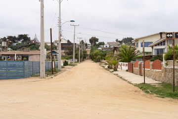 Fototapeta na wymiar Dirt road on empty street by Algarrobo beach on cloudy day in Chile. Pandemic lockdown, quarantine concepts