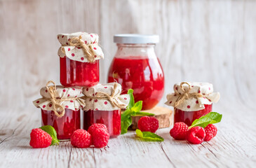 Raspberry marmalade in small glasses is placed on wooden desk. Homemade jam from fresh raspberries. Fresh and healthy cooking.