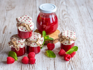 Raspberry marmalade in small glasses is placed on wooden desk. Homemade jam from fresh raspberries. Fresh and healthy cooking.