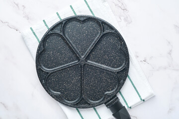 Empty frying pan black, skillet with stone nonstick coating for baking pancakes in shape of breakfast hearts and ingredients on gray concrete table background. Breakfast for Valentines Day. Top view.