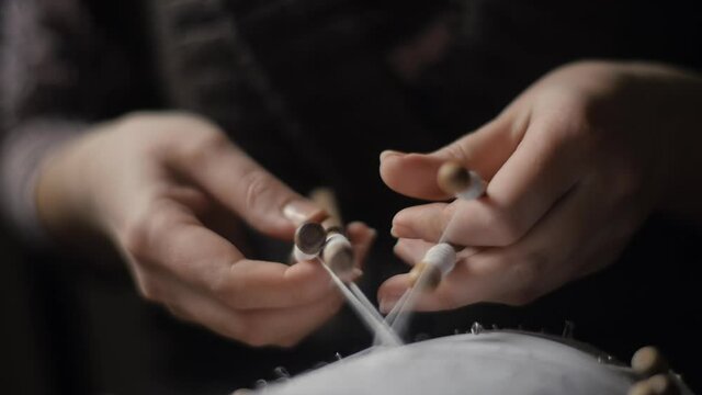 Female hands weaving and tightening lace with bobbins