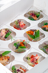 Portions of Seafood snacks in a white box for delivery. Catering service with a variety of dishes on the table