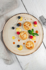 Pancakes with cottage cheese for breakfast. Cheesecakes with fresh raspberries and blueberries on a plate, top view