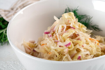 Sauerkraut in a white bowl - vitamins and antioxidants. Salad of pickled and chopped cabbage, close-up