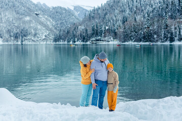 winter travel across Europe. view of the alpine lake with snow. portrait of happy family of travelers with child