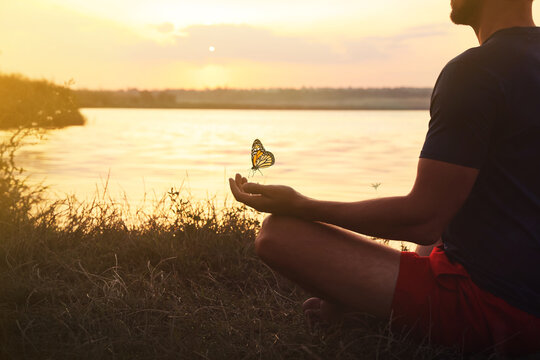 Man meditating near river at sunset, closeup. Space for text
