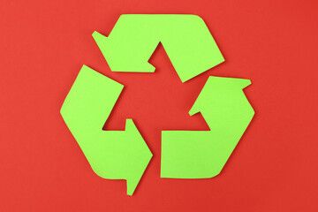 Icon of recycling made of green paper on a red background, the concept of protection, preservation of the environment