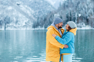 winter travel across Europe. view of the alpine lake with snow. portrait of an adult couple of enamored travelers on the shore of a high-mountain lake.