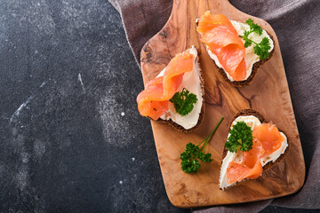 Mini sandwiches with salmon, curd cheese, parsley and rye bread in form of hearts. Valentine's day homemade creative food. Love breakfast design. Selective focus and copy space