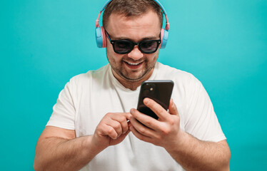 Close-up portrait of funny guy dancing and listening to music using a smartphone music application in headphones . Party man
