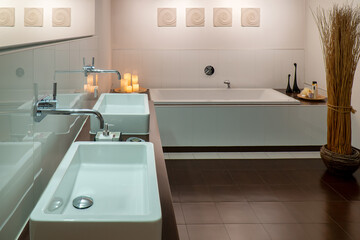 Modern bathroom in white and brown with two sinks and wooden top.