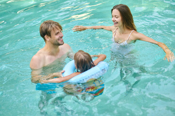 Parents teaching theri daughter to swim and looking involved