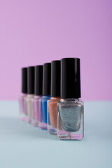 Bright multicolored, purple, brown, blue nail polish on a purple background. A slender row of jars