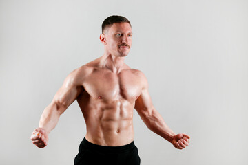 Professional bodybuilder posing over isolated white background. Studio shot of a fitness trainer flexing the muscles. Close up, copy space.