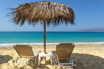 Two sun loungers and a parasol on a sandy Mediterranean beach