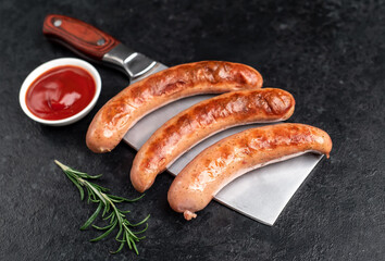 grilled sausages on a knife on a stone background