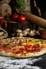 Italian Pizza Four Seasons (Pizza Quattro Stagioni) with different ingredients on the wooden table in the kitchen