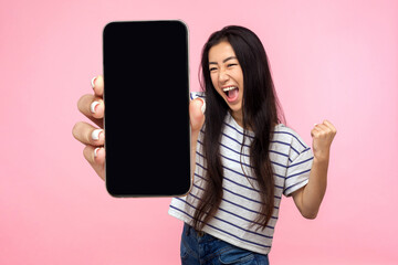 Portrait of euphoric happy joyful girl with long hair screaming with happiness showing mobile...