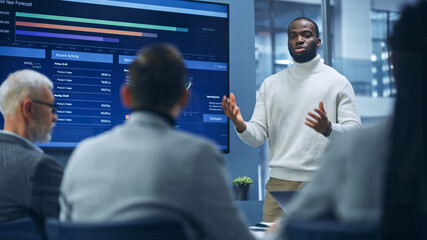 Diverse Modern Office: Portrait of Successful Black Businessman Uses TV Screen with Big Data,...