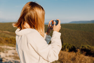 Blonde woman photography with smartphone. Girl shooting landscapes on smartphone