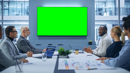 Multi-Ethnic Office Conference Room Meeting: Diverse Team of Successful Managers, Executives Talk, Use Green Screen Chroma Key TV. Group of Businesspeople Work on Strategy for an e-Commerce Startup