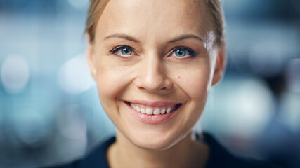 Portrait of Gorgeous Caucasian Woman with Deep Blue Eyes, Blonde Hair, Perfect Smile. Beautiful Girl Looks up at the Camera Happily. Abstract Bokeh out of Focus Background. Close-up Shot