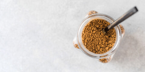 Glass jar of instant coffee with a spoon top view. Copy space.