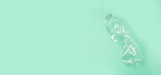Used rumpled plastic bottle on green background. Ecology problem. Top view, copy space. Plastic trash.