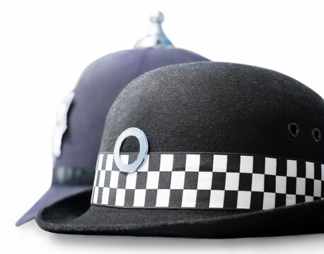 Law enforcement careers concept. Headwear similar in style to UK police- female Chief constable patrol hat in front of Male mobilefoot patrol Sergeant/Constable custodian helmet as worn at incidents.