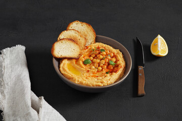 Traditional Middle east appetizer Hummus served with fresh pita bread and herbs, seasoned with extra virgin olive oil and paprika in vintage ceramic plate.