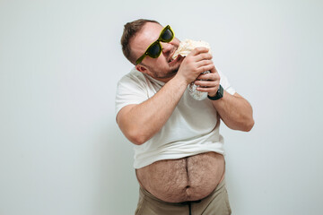 Overweight funny man with a belly hanging out of his pants eating tasty shawarma. Glutton