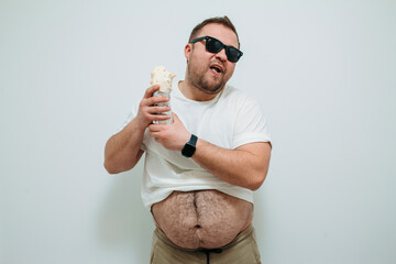 Overweight funny man with a belly hanging out of his pants eating tasty shawarma. Glutton