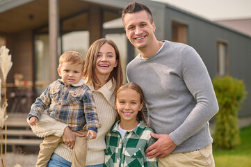 Young parents and children embracing standing looking at camera