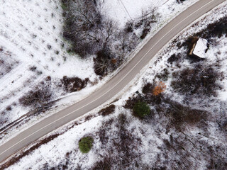 High angle top down aerial view drone image on road trough the trees and forest in mountain range covered with white snow in winter day near Knjazevac in Serbia - Travel journey and vacation concept