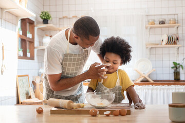 African American Father playing touching his little boy nose with flour