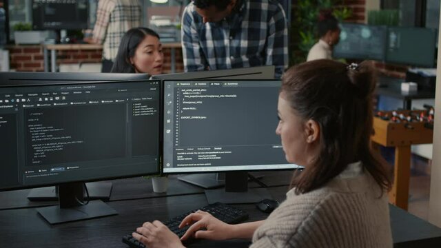 Software programer writing code in front of multiple computer screens displaying artificial intelligence algorithm. Developer coding database while colleagues doing online cloud computing.