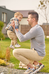 Man sitting sideways to camera and raising child
