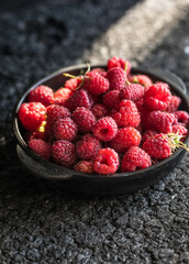 Raspberries in bowl on a dark wooden table, selective focus. Ingredients for raspberry juice or desserts. Raspberries on bowl. Raspberry with copy space for text. Various fresh summer berry . 