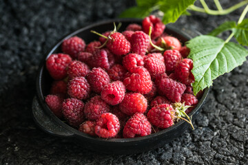 Raspberries in bowl on a dark wooden table, selective focus. Ingredients for raspberry juice or desserts. Raspberries on bowl. Raspberry with copy space for text. Various fresh summer berry . 
