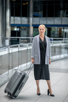 Cheerful businesswoman with her baggage standing at the airport terminal