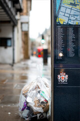 Obraz premium London, December 27th 2021: A bag of garbage next to a London street sign