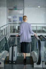 Tourist with the luggage going down the moving staircase