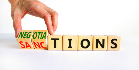 Sanctions or negotiations symbol. Businessman turns cubes, changes the word sanctions to negotiations. Beautiful white table, white background, copy space. Business, sanction or negotiation concept.