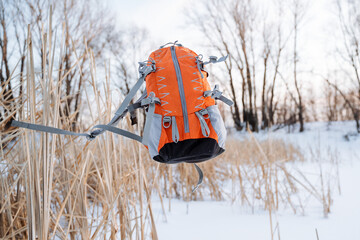 The orange-colored backpack hung in the air. The concept of camping equipment. The flight of a backpack against the background of the forest. Sports equipment for climbers.