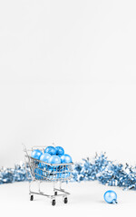 Shopping trolley full of blue Christmas baubles balls and tinsel composition.